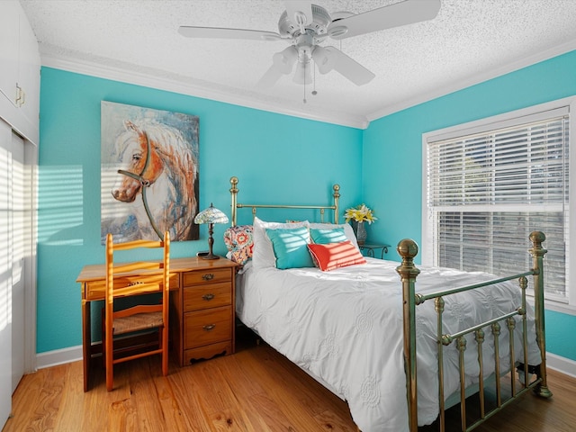 bedroom featuring ceiling fan, light hardwood / wood-style floors, ornamental molding, and a textured ceiling