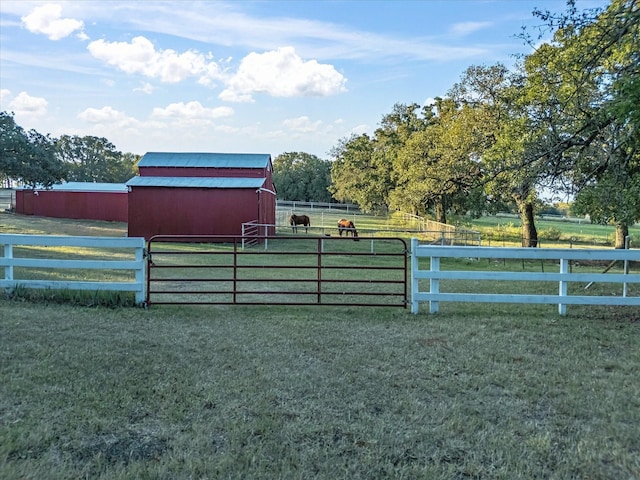 exterior space featuring a rural view, an outdoor structure, and a lawn