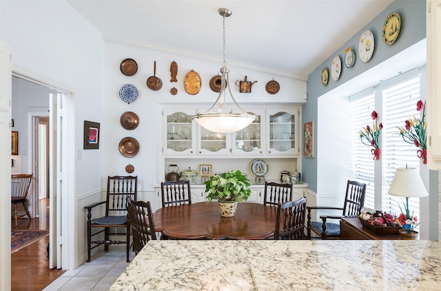 dining space with ornamental molding, light wood-type flooring, and vaulted ceiling