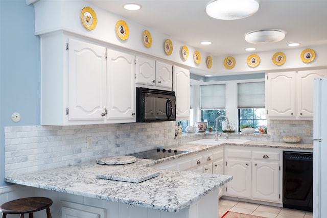 kitchen with kitchen peninsula, white cabinets, and black appliances