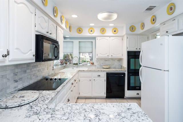 kitchen with white cabinetry, black appliances, light tile patterned floors, and decorative backsplash