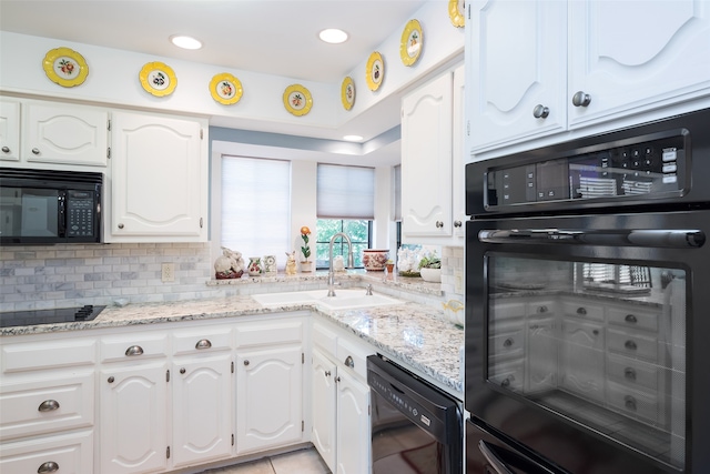 kitchen featuring black appliances, sink, white cabinets, light stone counters, and decorative backsplash