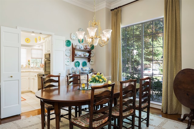 dining space with light hardwood / wood-style flooring, ornamental molding, and a chandelier