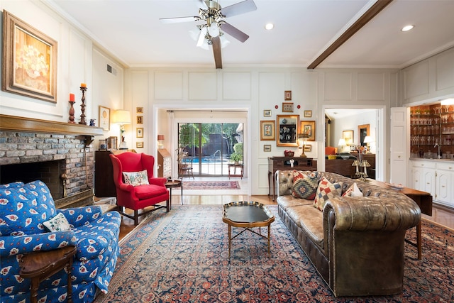 living room featuring ornamental molding, hardwood / wood-style floors, ceiling fan, and a brick fireplace