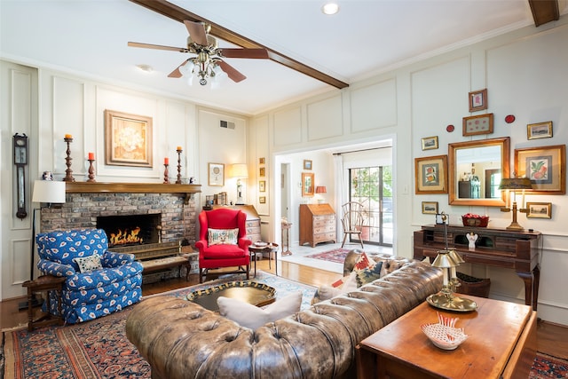 living room with crown molding, hardwood / wood-style floors, beam ceiling, and a brick fireplace