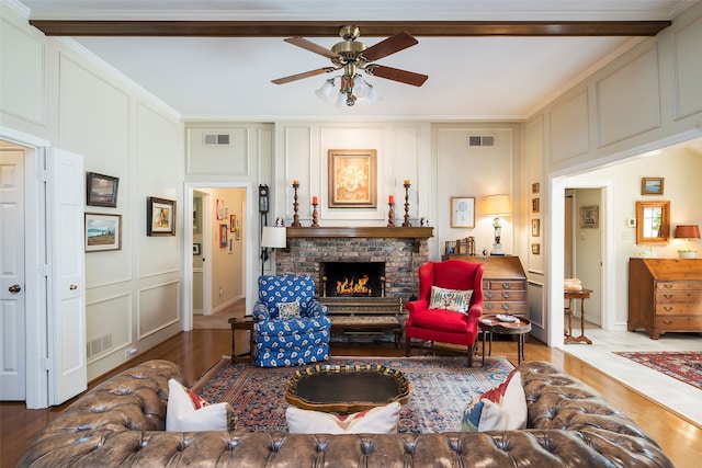 living room with crown molding, dark wood-type flooring, a fireplace, and ceiling fan