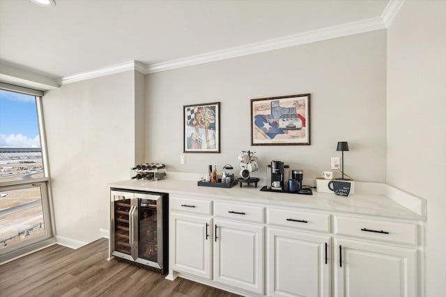 bar with crown molding, wine cooler, a bar, and wood finished floors