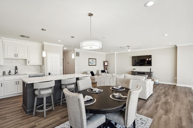 dining space with crown molding, sink, light wood-type flooring, and ceiling fan