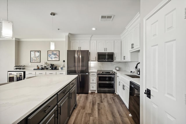 kitchen with white cabinetry, stainless steel appliances, and decorative light fixtures