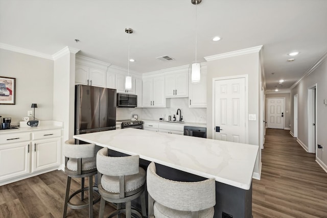 kitchen with stainless steel appliances, a center island, white cabinets, light stone counters, and dark hardwood / wood-style flooring