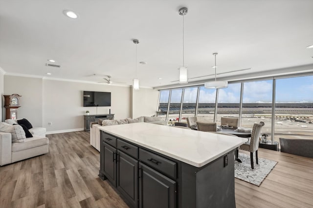 kitchen with a center island, ceiling fan, decorative light fixtures, crown molding, and light hardwood / wood-style flooring