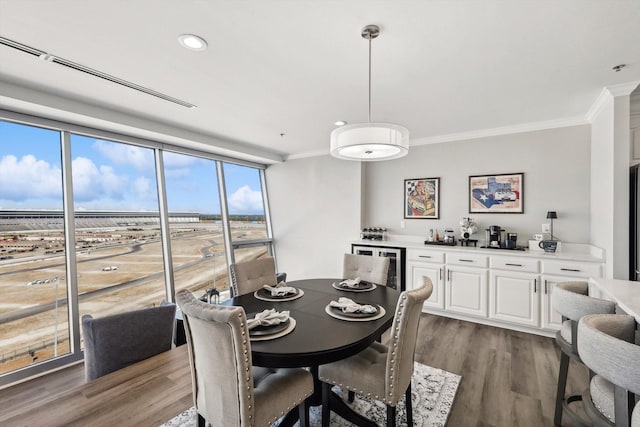 dining room with recessed lighting, wood finished floors, crown molding, and indoor bar