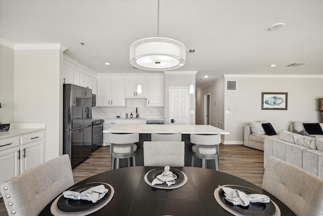 dining space with crown molding, sink, and dark hardwood / wood-style flooring