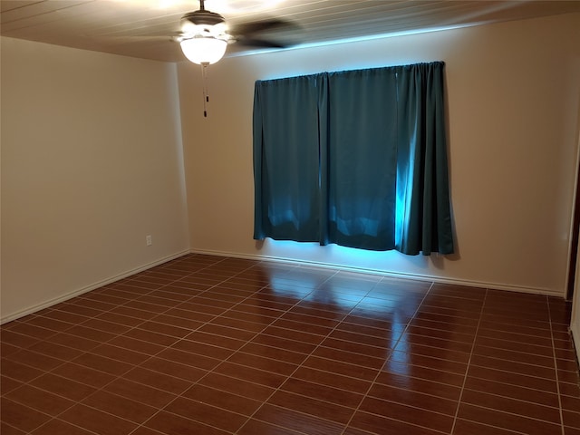 empty room featuring ceiling fan and dark tile patterned floors