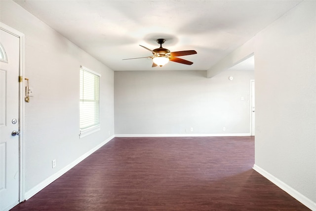 unfurnished room featuring beamed ceiling, ceiling fan, and dark wood-type flooring