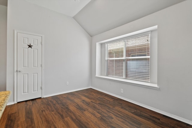 spare room featuring lofted ceiling and dark hardwood / wood-style flooring