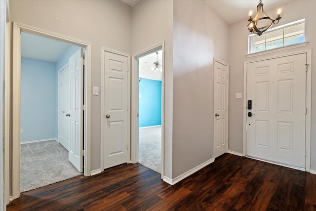 foyer featuring dark wood-type flooring and ceiling fan with notable chandelier