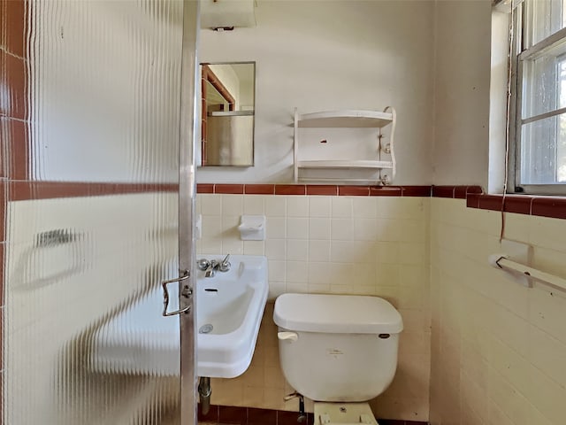 bathroom with toilet and tile walls