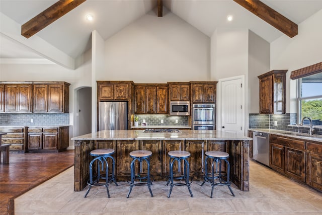 kitchen with a spacious island, appliances with stainless steel finishes, sink, and decorative backsplash