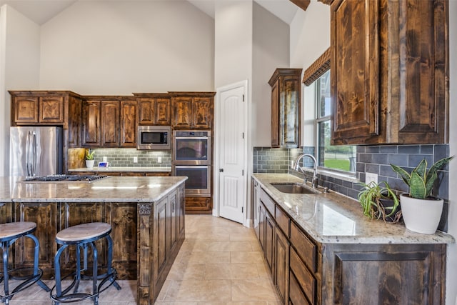 kitchen with light stone counters, appliances with stainless steel finishes, sink, and backsplash