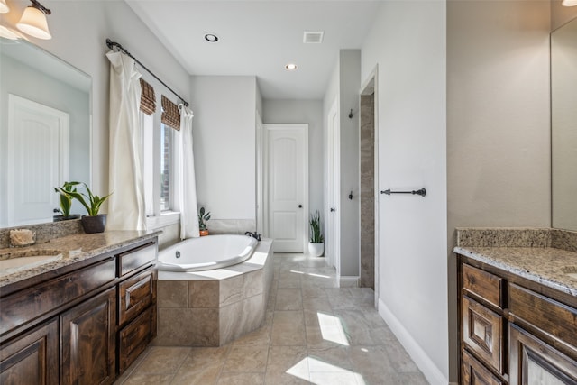 bathroom featuring vanity and a relaxing tiled tub