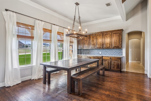 dining room with a notable chandelier, ornamental molding, beam ceiling, and dark wood-type flooring