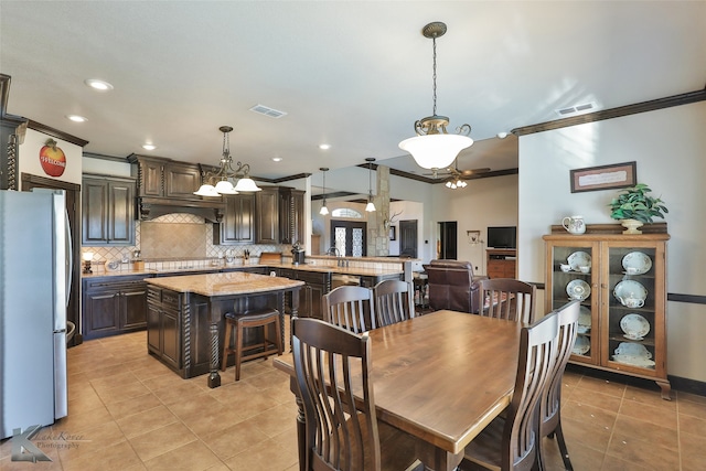 tiled dining room featuring crown molding and a chandelier