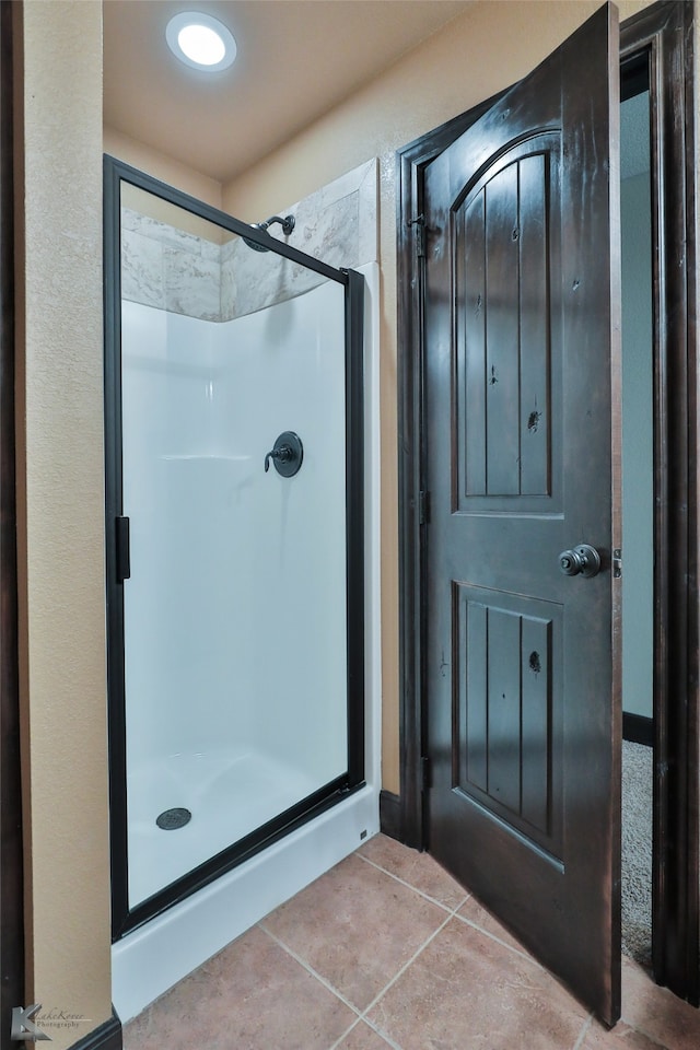 bathroom with an enclosed shower and tile patterned flooring