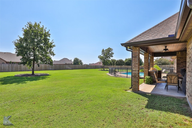 view of yard with a fenced in pool, a patio, and ceiling fan