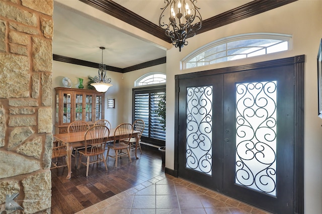 foyer with a wealth of natural light, dark wood-type flooring, crown molding, and french doors