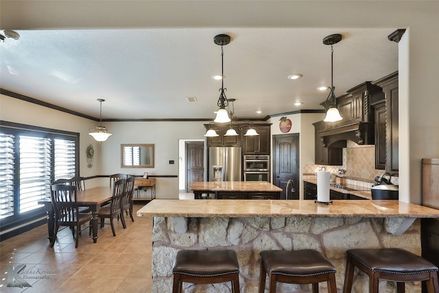 kitchen featuring decorative light fixtures, a kitchen bar, stainless steel appliances, and tasteful backsplash