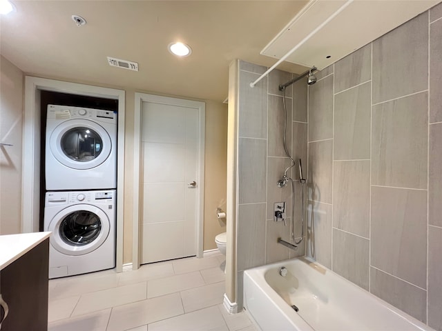 full bathroom featuring tile patterned floors, toilet, tiled shower / bath combo, vanity, and stacked washer / dryer