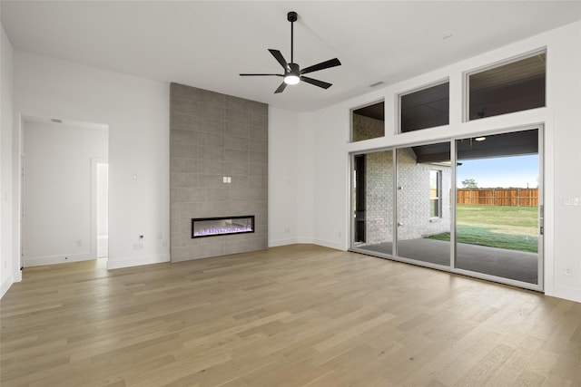 unfurnished living room with a tile fireplace, ceiling fan, and light hardwood / wood-style flooring