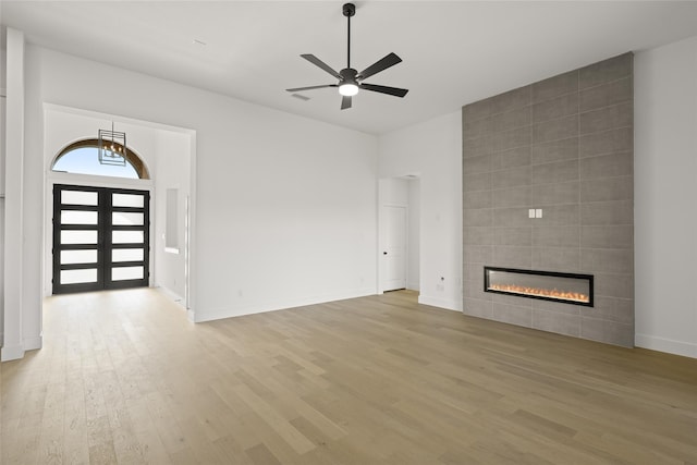 unfurnished living room featuring ceiling fan, wood-type flooring, and a tile fireplace