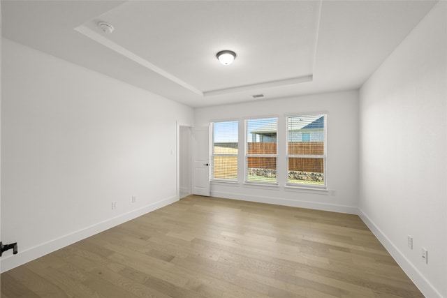 unfurnished room featuring a raised ceiling and light wood-type flooring