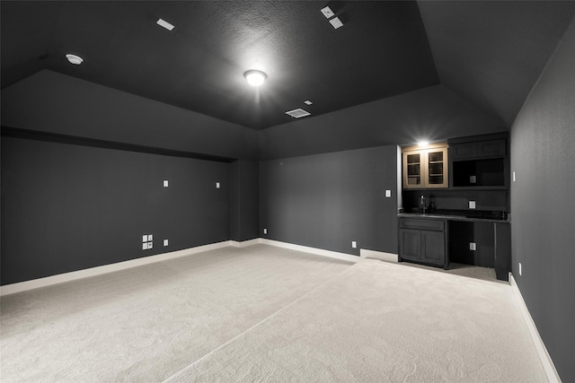 carpeted cinema featuring indoor wet bar, lofted ceiling, and a textured ceiling