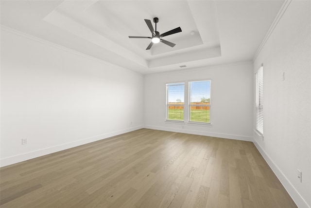 spare room with a raised ceiling, crown molding, light hardwood / wood-style flooring, and ceiling fan