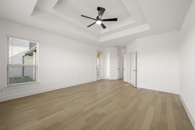 spare room with ceiling fan, ornamental molding, a tray ceiling, and light hardwood / wood-style flooring