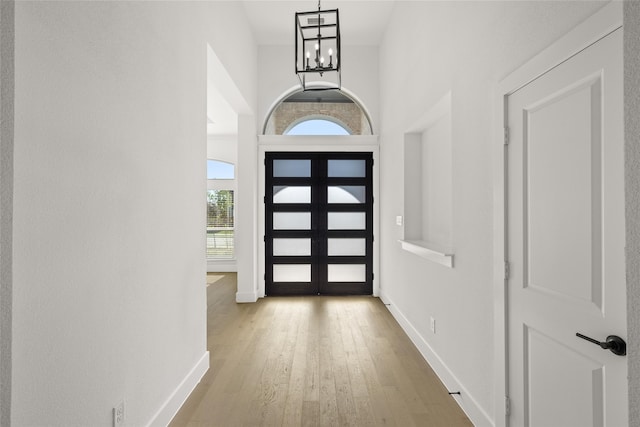 entrance foyer featuring a chandelier, a towering ceiling, and light wood-type flooring