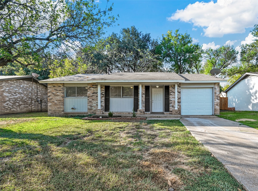 ranch-style home featuring covered porch, a front yard, and a garage