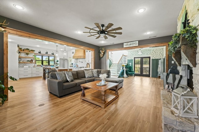 living room featuring light hardwood / wood-style floors, french doors, a fireplace, and ceiling fan