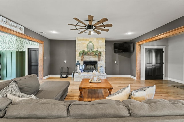 living room with ceiling fan, wood-type flooring, and a fireplace