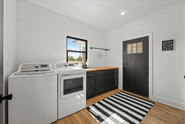 washroom with light hardwood / wood-style flooring, washer and dryer, and cabinets