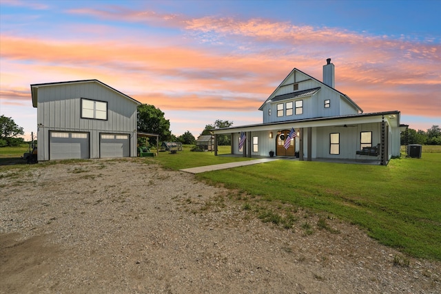 modern inspired farmhouse featuring a yard, covered porch, cooling unit, and a garage