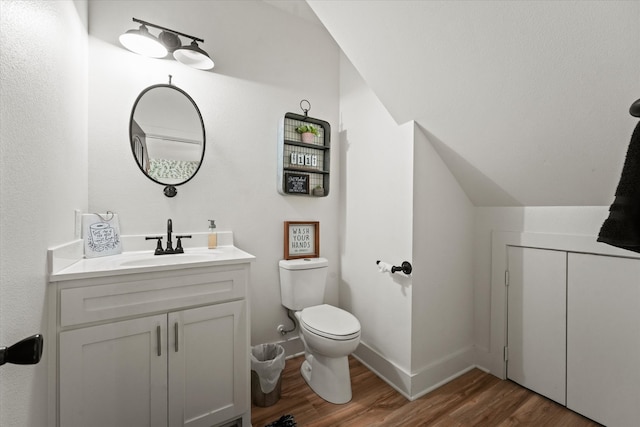 bathroom with vanity, toilet, hardwood / wood-style flooring, and lofted ceiling