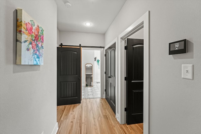 corridor featuring a barn door and light hardwood / wood-style flooring