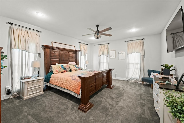 bedroom with multiple windows, dark carpet, and ceiling fan