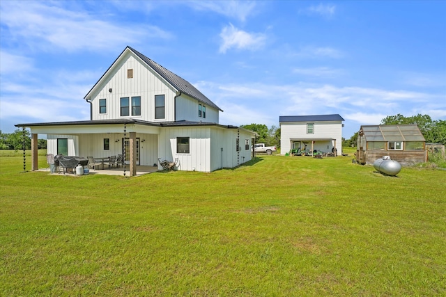 rear view of property featuring a patio, an outbuilding, and a lawn