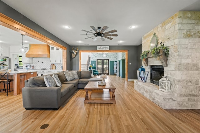 living room with light hardwood / wood-style floors, a wealth of natural light, a fireplace, and ceiling fan