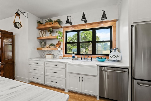 bar featuring sink, white cabinetry, light hardwood / wood-style flooring, and stainless steel appliances